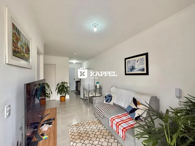 Sala de estar com sofá e mesa de jantar em um apartamento claro.