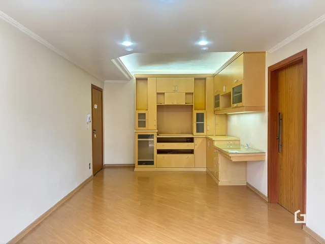 Interior de uma cozinha e sala de estar com piso de madeira clara.