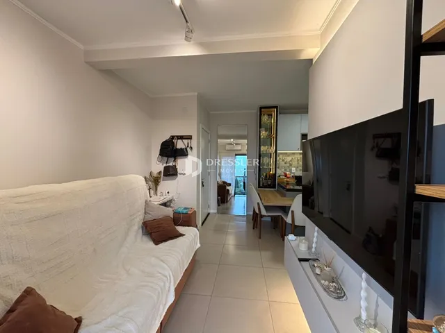Sala de estar com sofá branco e piso claro em um imóvel no Brasil.