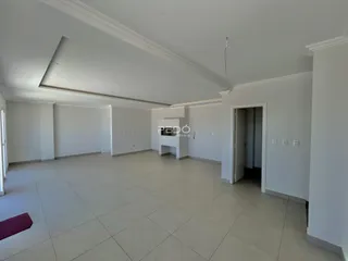 Foto de uma sala ampla e vazia com piso de cerâmica em um imóvel.