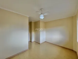 Ambiente interno de uma sala com piso de madeira clara e paredes claras.
