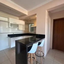 Foto de uma cozinha com bancada escura e armários brancos.