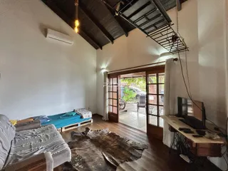 Sala de estar com piso de madeira e acesso a uma área externa.