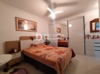Quarto com cama e paredes brancas em um imóvel.