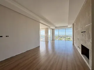 Sala ampla com piso de madeira e vista para a paisagem.
