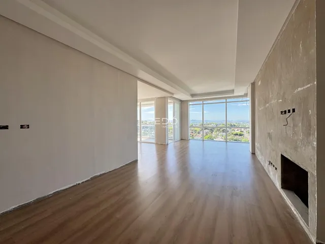 Sala ampla com piso de madeira e vista para a paisagem.