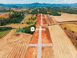 Vista aérea de uma propriedade rural com campos de terra e um corpo d'água.