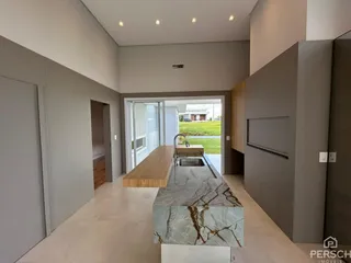 Cozinha moderna com ilha de mármore e acesso a área externa.