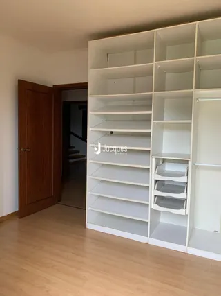 Interior de um ambiente com piso de madeira e estante branca.