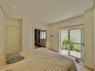 Quarto com cama e porta de vidro abrindo para a área externa.