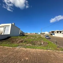 Vista externa de um terreno com vegetação seca sob um céu azul claro.