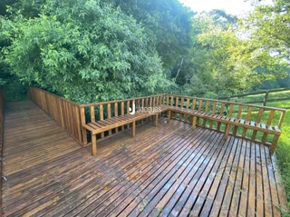 Deck de madeira ao ar livre com vegetação densa ao fundo.