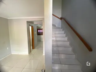 Hall de entrada com piso de cerâmica e paredes brancas.