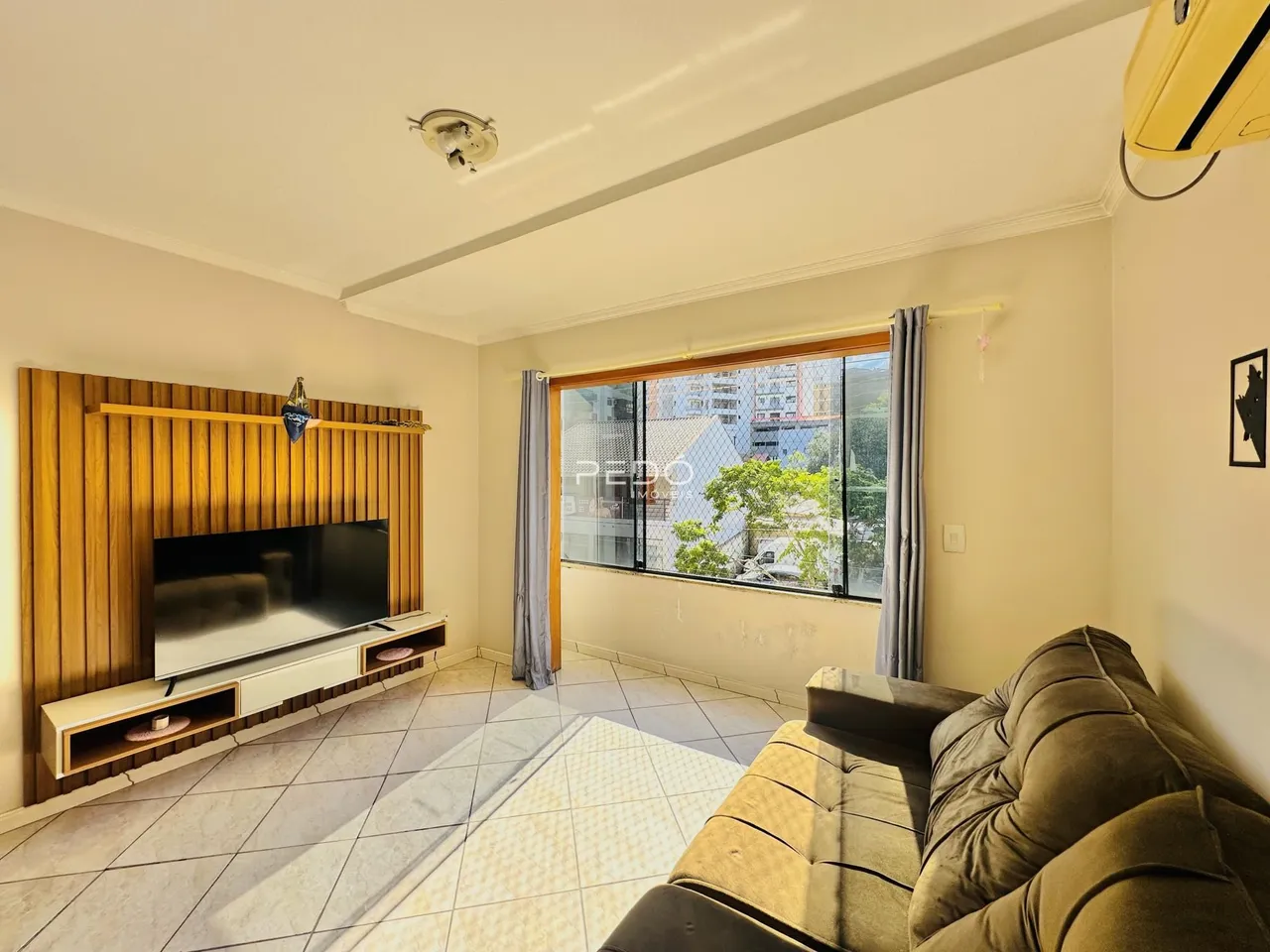 Sala de estar com parede de madeira e janela de vista para a cidade.