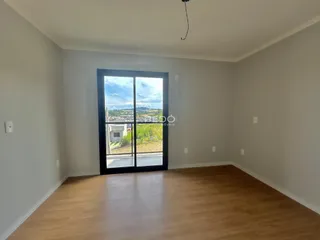 Sala de estar com piso de madeira e vista para a paisagem externa.