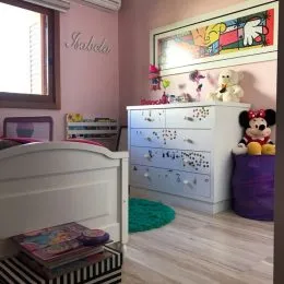 Quarto com cama e cômoda brancas em um ambiente interno.
