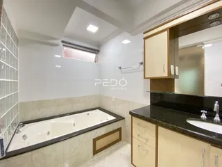 Banheiro com banheira e revestimento cerâmico nas paredes.