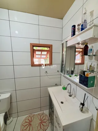 Banheiro com revestimento de azulejos brancos.