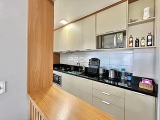 Cozinha moderna com armários brancos e madeira clara.