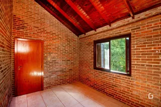 Interior de uma sala com paredes de tijolo aparente e teto de madeira.