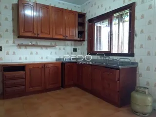 Uma cozinha com armários de madeira e janela em um imóvel no Brasil.