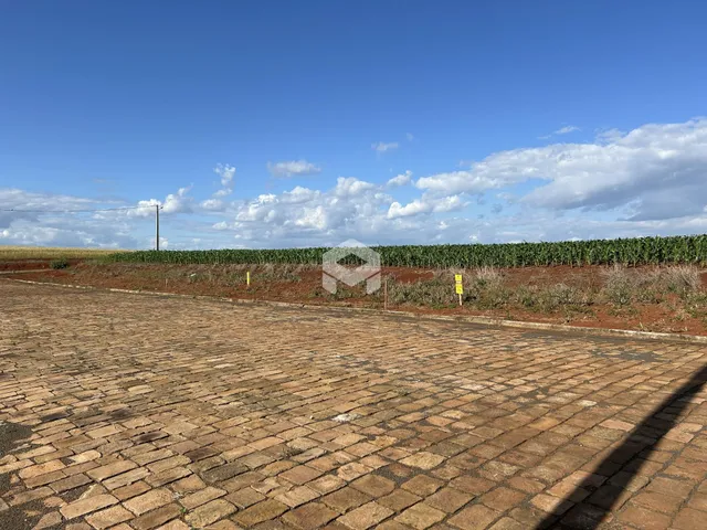 Vista da propriedade com área pavimentada e campo aberto ao fundo.
