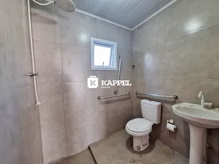 Banheiro com box de vidro, vaso sanitário e pia instalada.