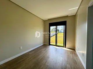Ambiente interno de uma sala com piso de madeira clara e parede bege.