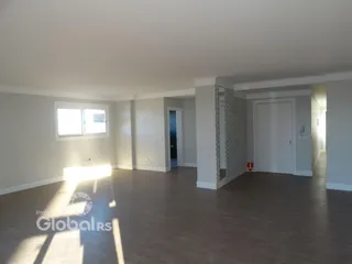 Sala de estar ampla com piso de madeira e luz natural.
