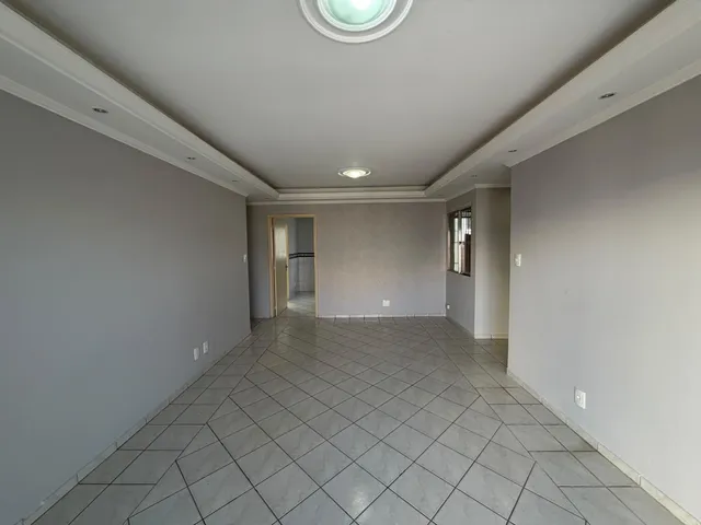 Corredor longo com piso de cerâmica claro e paredes em tom neutro.