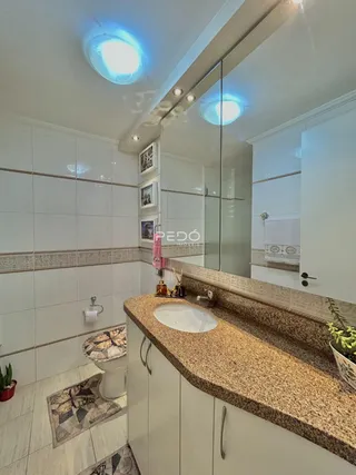 Banheiro com revestimento cerâmico e bancada de granito.