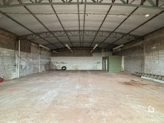 Espaço industrial com teto de metal e paredes de tijolo exposto.