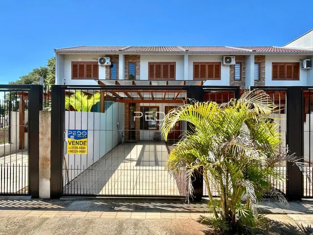 Fachada de uma residência em Lajeado, Brasil, com portão de ferro e vegetação.