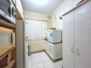 A cozinha apresenta piso cerâmico branco e armários brancos.