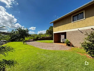Vista externa de uma residência com jardim e entrada de cascalho.