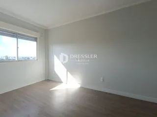 Ambiente interno de uma sala com piso de madeira clara e grande janela.