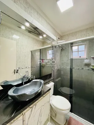 Interior de um banheiro moderno com azulejos e box de vidro.
