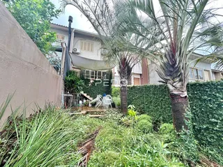 Vista da fachada de uma residência em Lajeado, Brasil, com vegetação densa no primeiro plano.