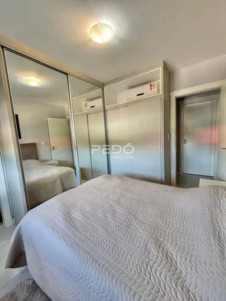 Quarto com cama grande e espelho refletindo o ambiente.