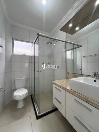 Banheiro moderno com box de vidro e bancada de granito.