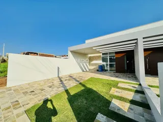 Fachada moderna de uma residência com área externa pavimentada e gramada.