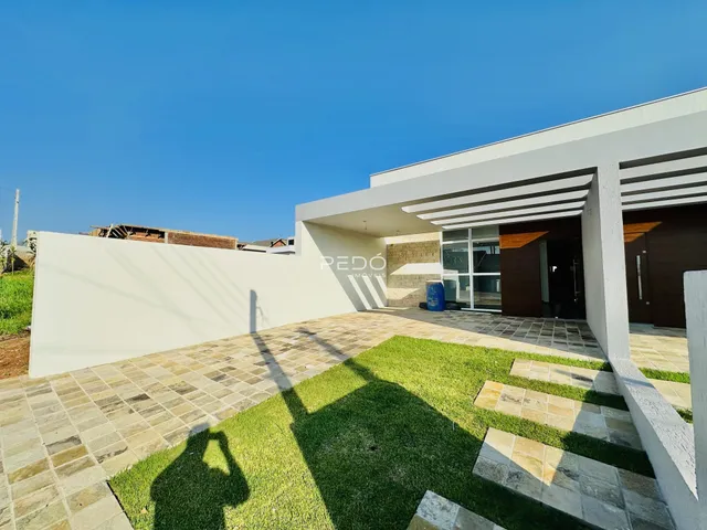 Fachada moderna de uma residência com área externa pavimentada e gramada.