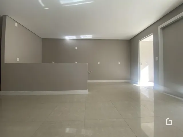 Ambiente interno de uma sala ampla com paredes cinzas e piso claro.