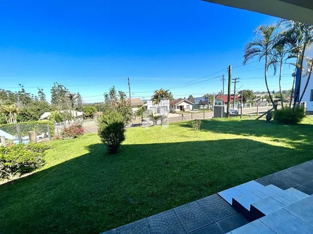 Vista de um gramado verde com árvores sob um céu azul.
