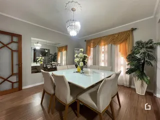 Sala de jantar com mesa de vidro e cadeiras em um imóvel no Brasil.