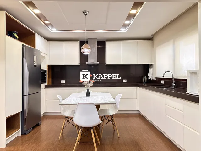 Cozinha moderna com armários brancos e mesa de jantar em ambiente bem iluminado.