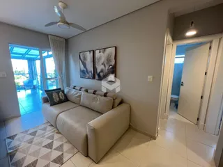 Sala de estar com sofá e portas de vidro que dão acesso ao exterior.