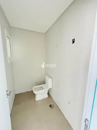 Foto de um banheiro com vaso sanitário branco e paredes brancas.