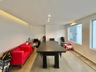 Sala de estar com sofá vermelho e mesa de jantar escura em um imóvel no Brasil.