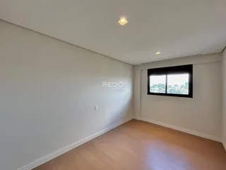 Ambiente interno de uma sala com piso de madeira e parede branca.